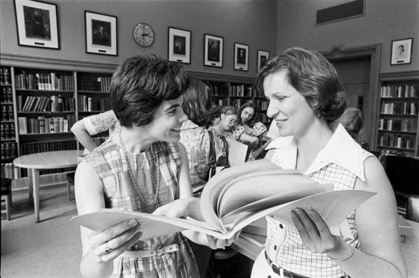 Black and white photo of two young women in the Lilly Library reading room.